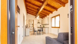 An interior with a wooden ceiling, a dining area, a sofa, and a kitchen. - Holiday Home 'Numero 1' with Shared Garden (Firenzuola)