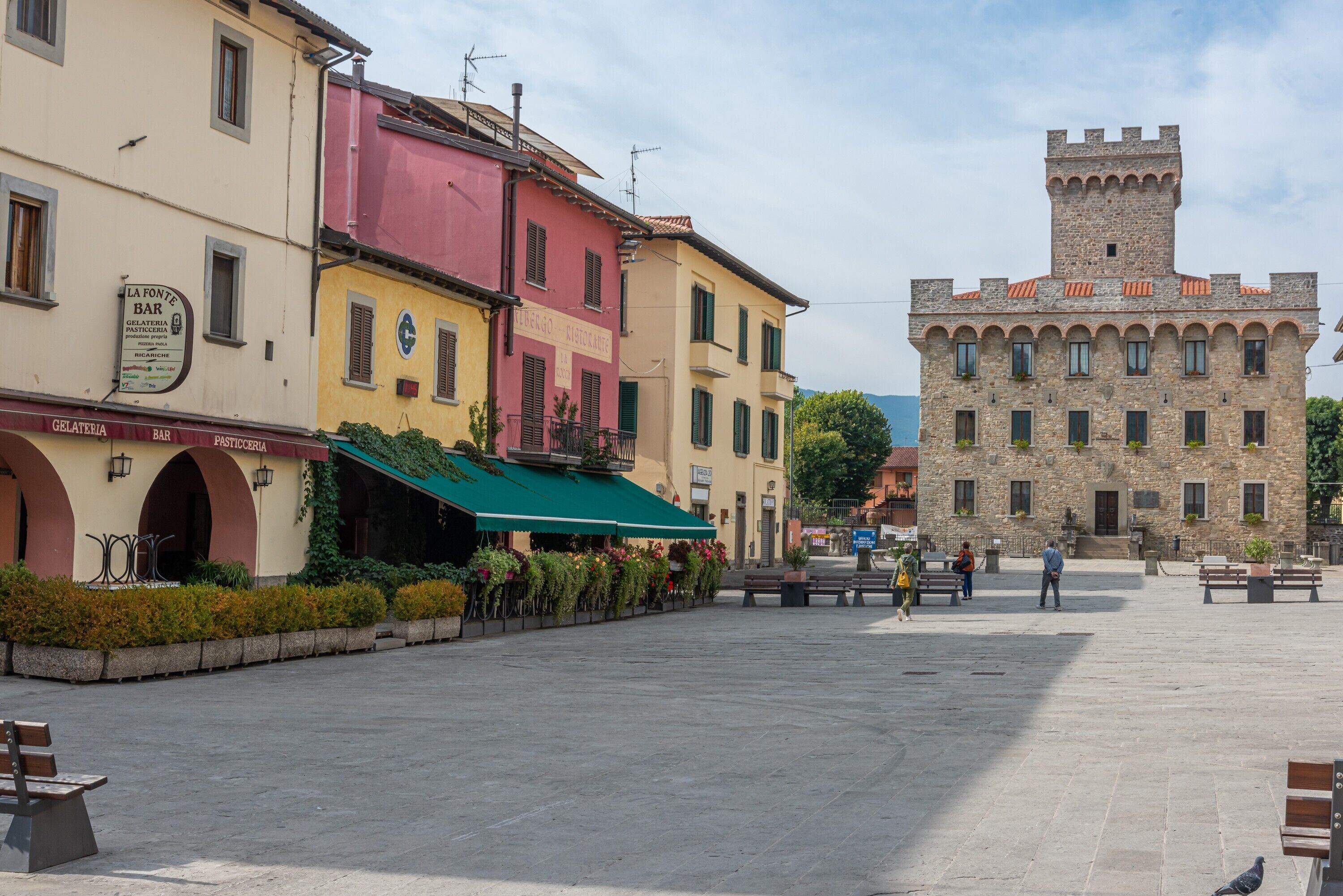 A public square with buildings, a tower, and benches.