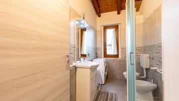 A bathroom with a wooden ceiling, a sink, a washing machine, and a toilet.