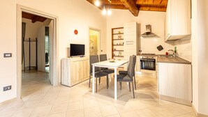 A modern kitchen with a dining area, wooden ceiling beams, and a television. - Holiday Home 'Numero 1' with Shared Garden (Firenzuola)