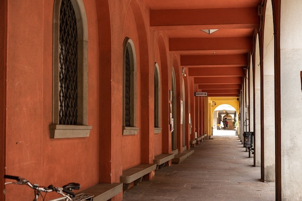 A corridor with arches, a bicycle, and a distant view of a building.