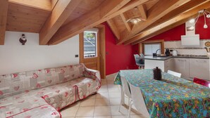 Una habitación acogedora con techo de madera, un sofá, una mesa de comedor y una zona de cocina.