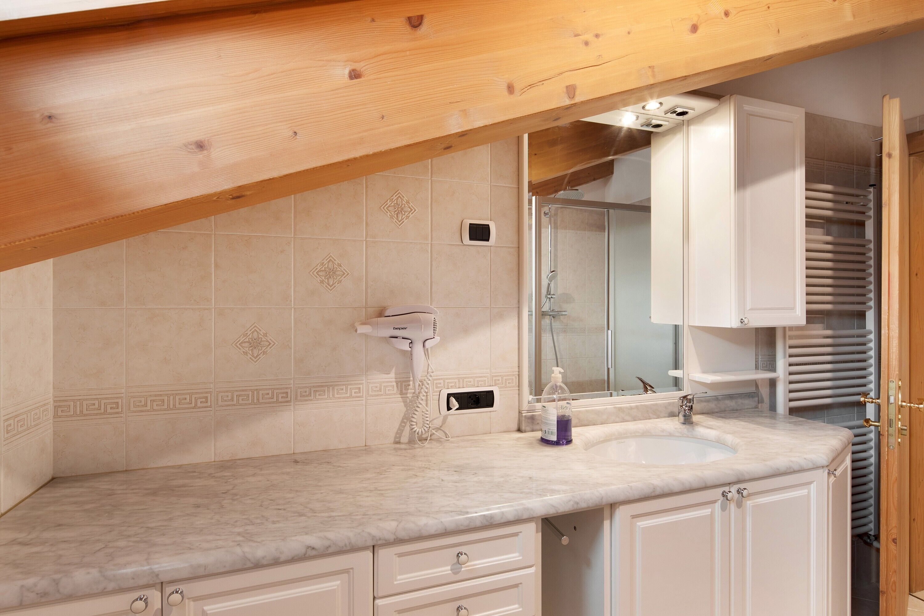 A bathroom with a marble countertop, a hairdryer, a sink, and a mirror.