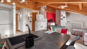 Una cocina con una isla central, una zona de comedor con mesa y sillas, y una pared de acento roja.