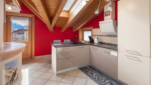 Una cocina con vigas de madera, pared roja y vistas a las montañas.