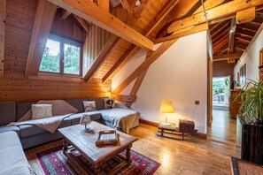 A cozy loft bedroom with a sloped ceiling, wooden beams, a sofa, a coffee table, and a lamp. - Apartment "Locdecharme" with Mountain Views, Private Terrace, and Wi-Fi (Les Clefs)