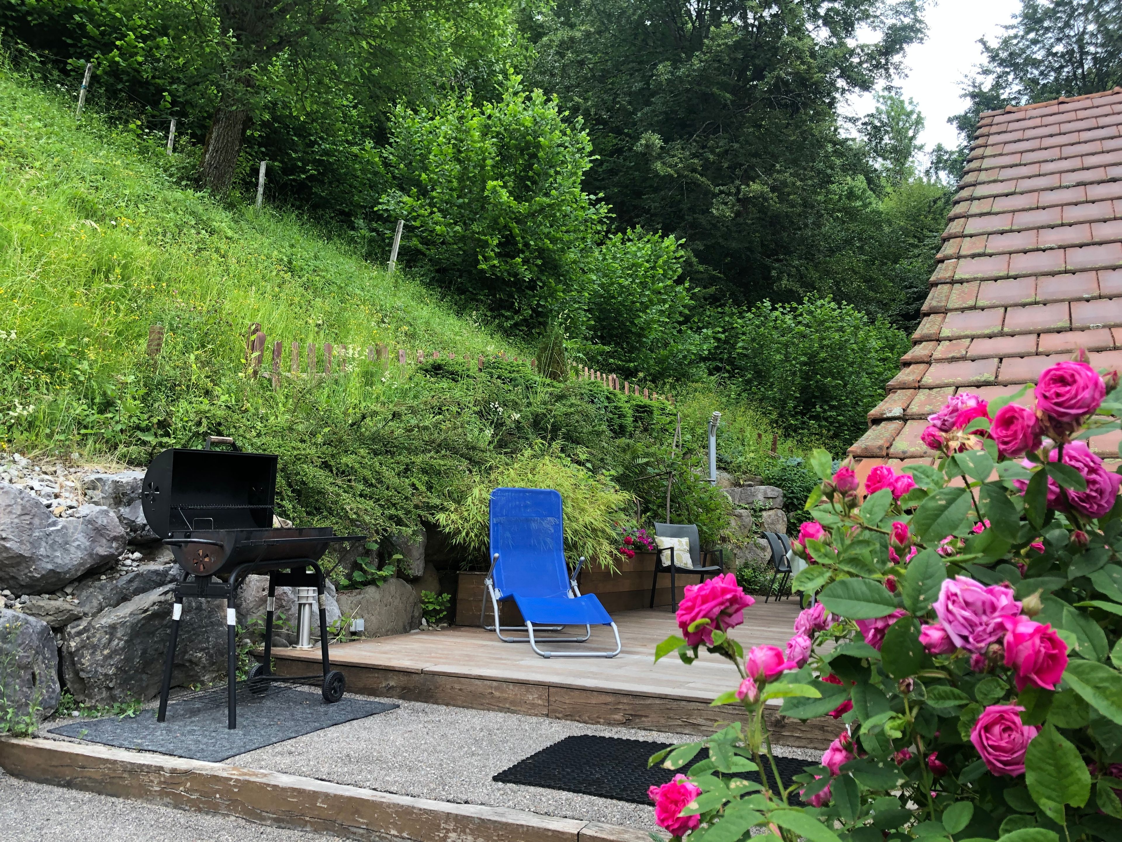 A patio area with a grill, a blue chair, and a small table.