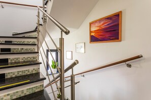 Un escalier avec des rampes en métal, une plante en pot et un tableau encadré au mur.