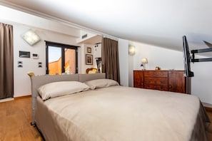 Une chambre à coucher avec un lit, une commode, un miroir, une télévision et une fenêtre avec des rideaux.