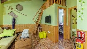 Une pièce avec un escalier en bois, une télévision, un extincteur et un lit à l’arrière-plan.