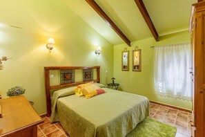 A bedroom with a bed, wooden headboard, two wall-mounted lamps, a small table, and a green rug. - Siesta y Brisca Country House in Ávila with Mountain Views, Terrace and Balcony (Manjabálago)