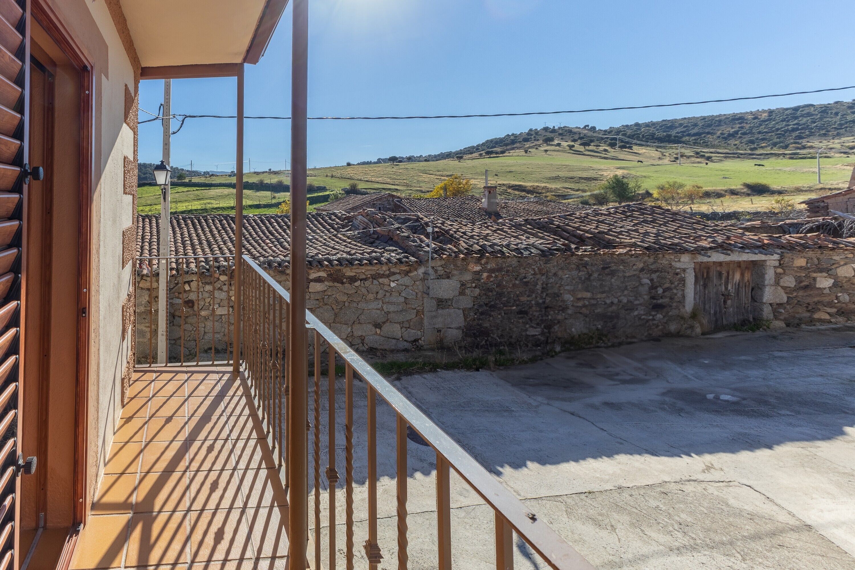 Un balcon donnant sur un paysage rural, avec des murs en pierre et un toit recouvert de tuiles.
