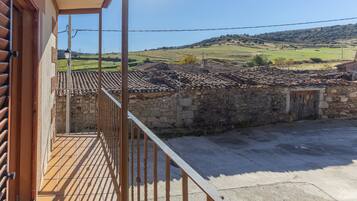 Un balcon donnant sur un paysage rural, avec des murs en pierre et un toit recouvert de tuiles.