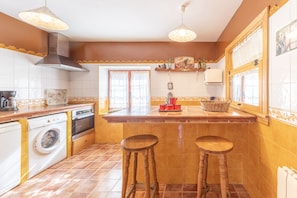 A kitchen with a washing machine, oven, and bar stools.