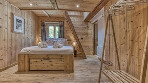 A wooden cabin bedroom with a bed, towels, and a window. - Magnificent traditional 4 bedroom farmhouse a walk from Chamonix centre (Chamonix)