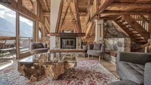 A spacious living area with a glass coffee table, two grey sofas, a stone fireplace, and a wooden ceiling. - Magnificent traditional 4 bedroom farmhouse a walk from Chamonix centre (Chamonix)