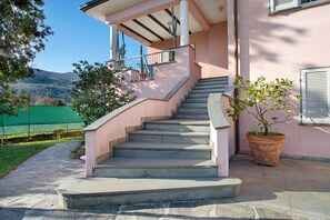 A staircase leading to a building with a pink exterior, a potted plant, and a view of a green landscape. - Villa 'Lucia' with Mountain Views, Private Terrace and Wi-Fi (Ameglia)