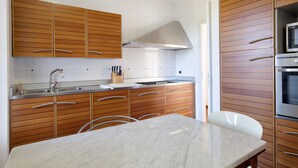 Eine moderne Küche mit Holzschränken, einer Edelstahl-Spüle und einer Marmorarbeitsplatte.