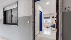 Ein Flur mit Fenster, einer blauen Tür und einer Leiter.