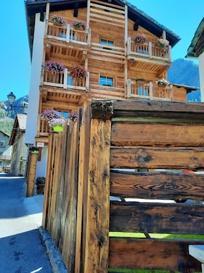 A wooden building with balconies, a wooden fence, and a street view.
