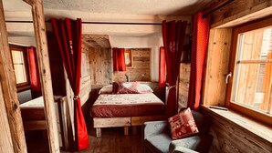 Une chambre à coucher rustique avec un lit en bois, un canapé et une fenêtre avec des rideaux.