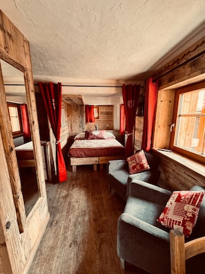 A rustic bedroom with a wooden bed, a sofa, and a window with curtains.