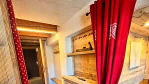 Une pièce rustique avec un banc en bois, une petite table en bois et un rideau rouge.