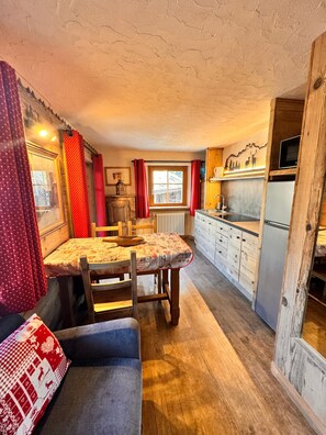 Une cuisine compacte comprenant une table à manger, des chaises, un canapé et un réfrigérateur.