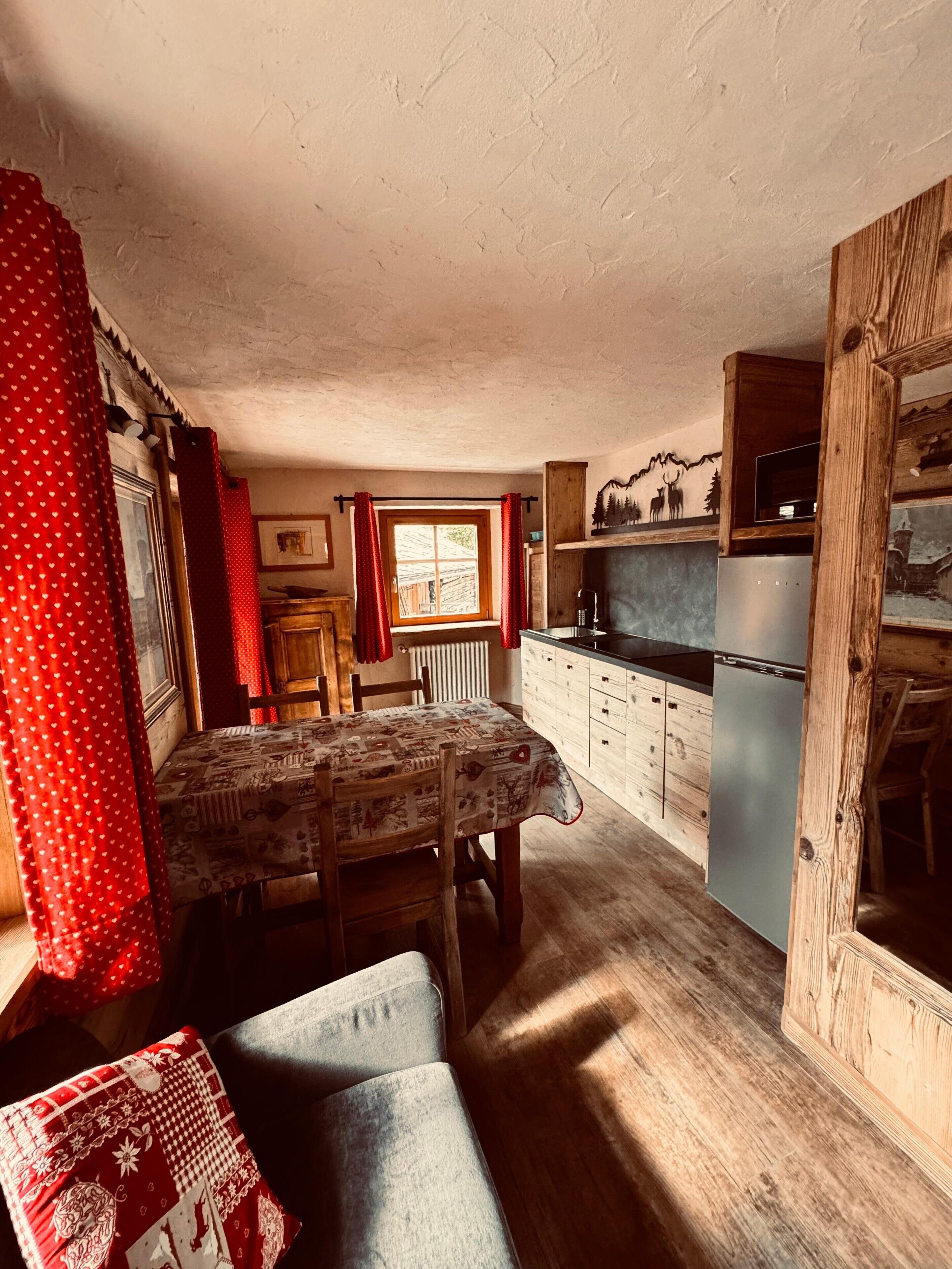 Eine gemütliche Küche mit Esstisch, Holzschränken und einem Kühlschrank.