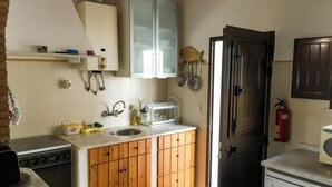 Une cuisine équipée d’une cuisinière, d’un évier, de meubles en bois, d’un réfrigérateur blanc et d’un extincteur.