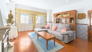 A living room with a sofa, a coffee table, a decorative cabinet, and a wall-mounted clock. - Villa 'Beautiful Deluxe 4 Bedroom' with Private Pool, Garden & Wi-Fi (Brescos)