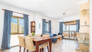 A spacious living area with a dining table, wicker chairs, a sofa, and a view of the sea. - Apartment 'Vistamar Sa Rapita' with Sea View, Wi-Fi and Air Conditioning (Sa Ràpita)