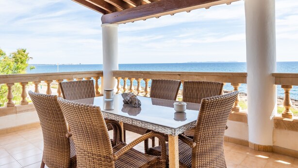 A covered outdoor dining area with wicker chairs and a table, overlooking the sea. - Apartment 'Vistamar Sa Rapita' with Sea View, Wi-Fi and Air Conditioning (Sa Ràpita)