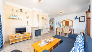 A living room with a TV, sofa, wooden coffee table, and a fireplace. - Apartment 'Vistamar Sa Rapita' with Sea View, Wi-Fi and Air Conditioning (Sa Ràpita)