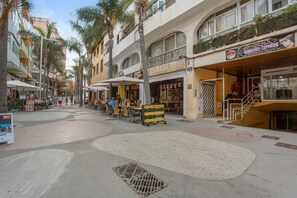 Una strada con tavolini all'aperto, un bar e un centro estetico.