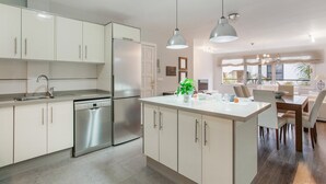 Una cocina moderna con armarios blancos, electrodomésticos de acero inoxidable e iluminación colgante.