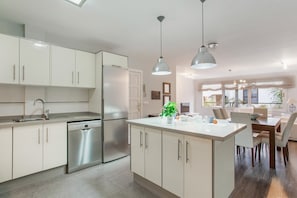 A modern kitchen with white cabinetry, stainless steel appliances, and pendant lighting.
