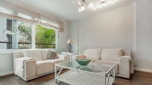 Una sala de estar moderna con dos sofás, una mesa de centro de vidrio y una lámpara.