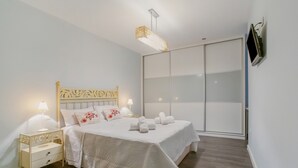 Un dormitorio con cama, mesitas de noche, televisión y puerta corredera.
