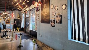 Eine Kunstgalerie mit modernem Industriedesign, inklusive einer großen Chandelier, Kunstwerken an den Wänden und einem Streifenvorhang.