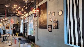 Ett konstgalleri med en modern, industriell design, med en stor kristallkrona, konstverk på väggarna och en randig gardin.