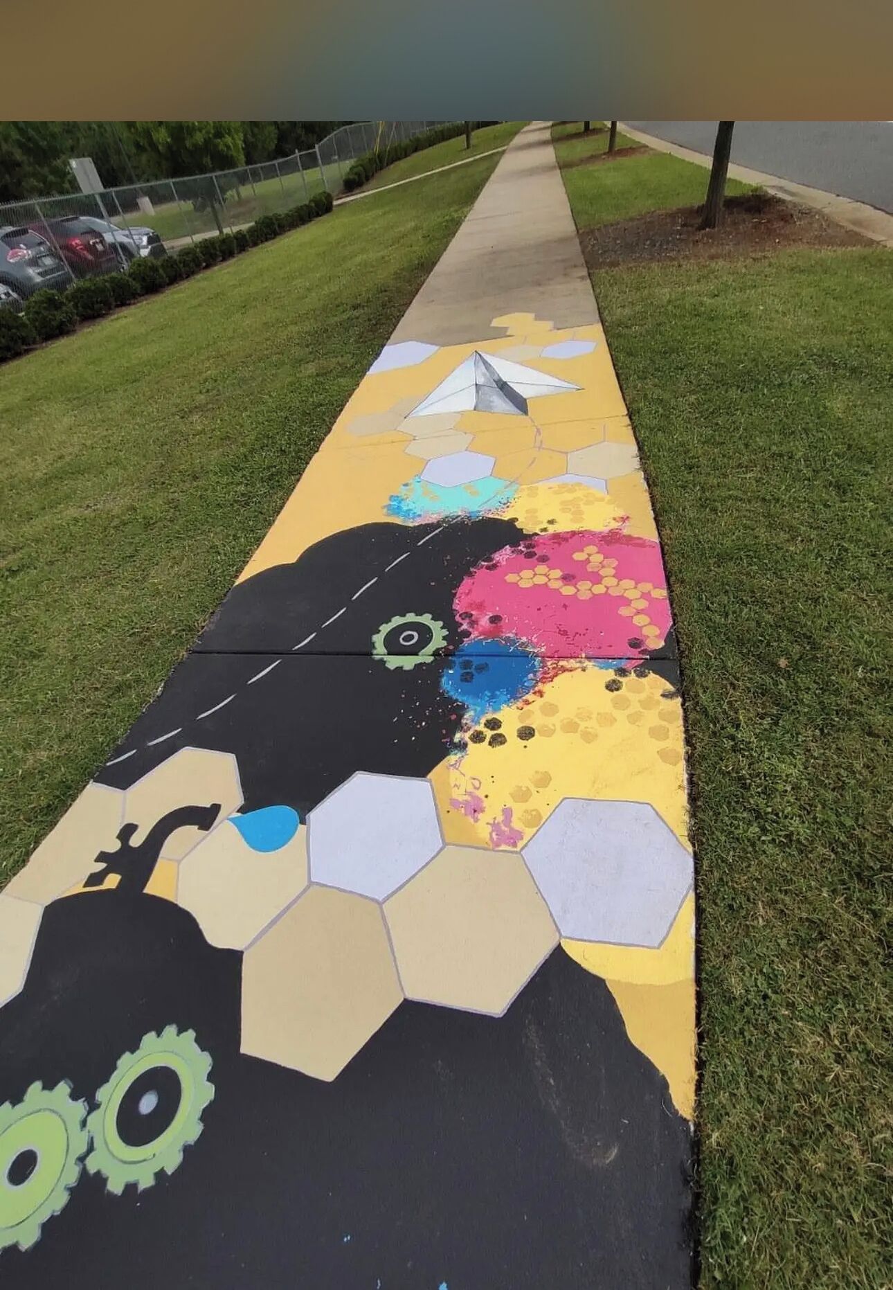 A colorful painted pathway with hexagonal patterns and mechanical designs.