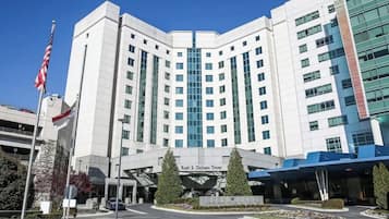 En modern byggnad som inrymmer ett medicinskt centrum, med en framträdande entré, flaggstänger och en klar himmel.