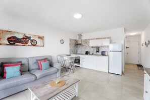 A modern kitchen with white cabinets, a microwave, and a refrigerator.