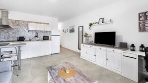 Una cocina moderna con armarios blancos, horno empotrado y comedor con mesa y sillas.