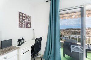 A room with a desk, chair, and a view of the outdoors.