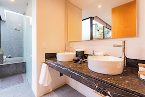A modern bathroom with two sinks, a large mirror, and a shower area.