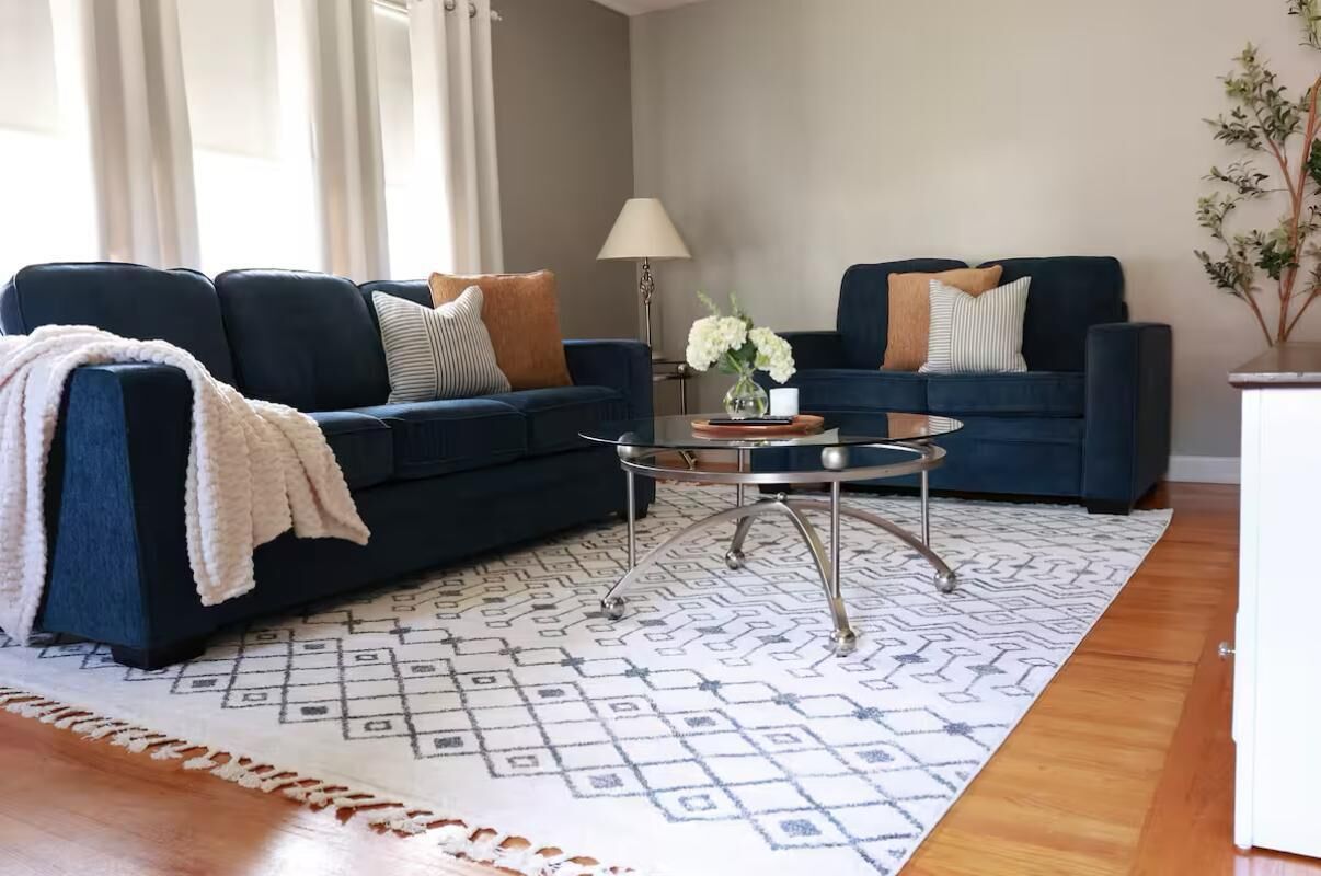 A living room with two dark blue sofas, a patterned rug, and a small round coffee table.