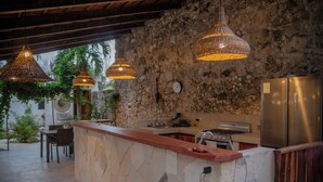 A kitchen with a stone countertop, a refrigerator, and hanging pendant lights. - Casa Cactus Buenavista  (Bacalar)