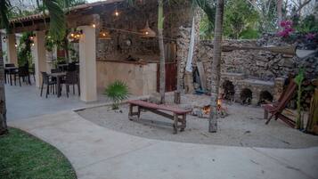 Un espace extérieur aménagé en terrasse, avec des murs en pierre, des meubles en bois et un foyer.
